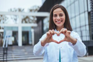 A young woman is making a heart symbol to promote women's health and encourage everyone to care for their hearts and love their bodies.