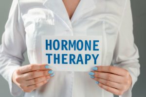 A woman holding card with hormone therapy lettering isolated on grey background.