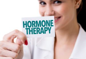 A female OB GYN holding a card that says Hormone Therapy.