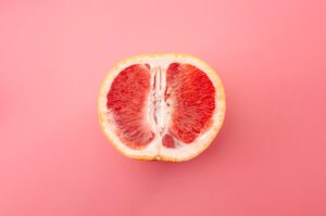 metaphor for female sexual organs concept with grapefruit isolated on pink background